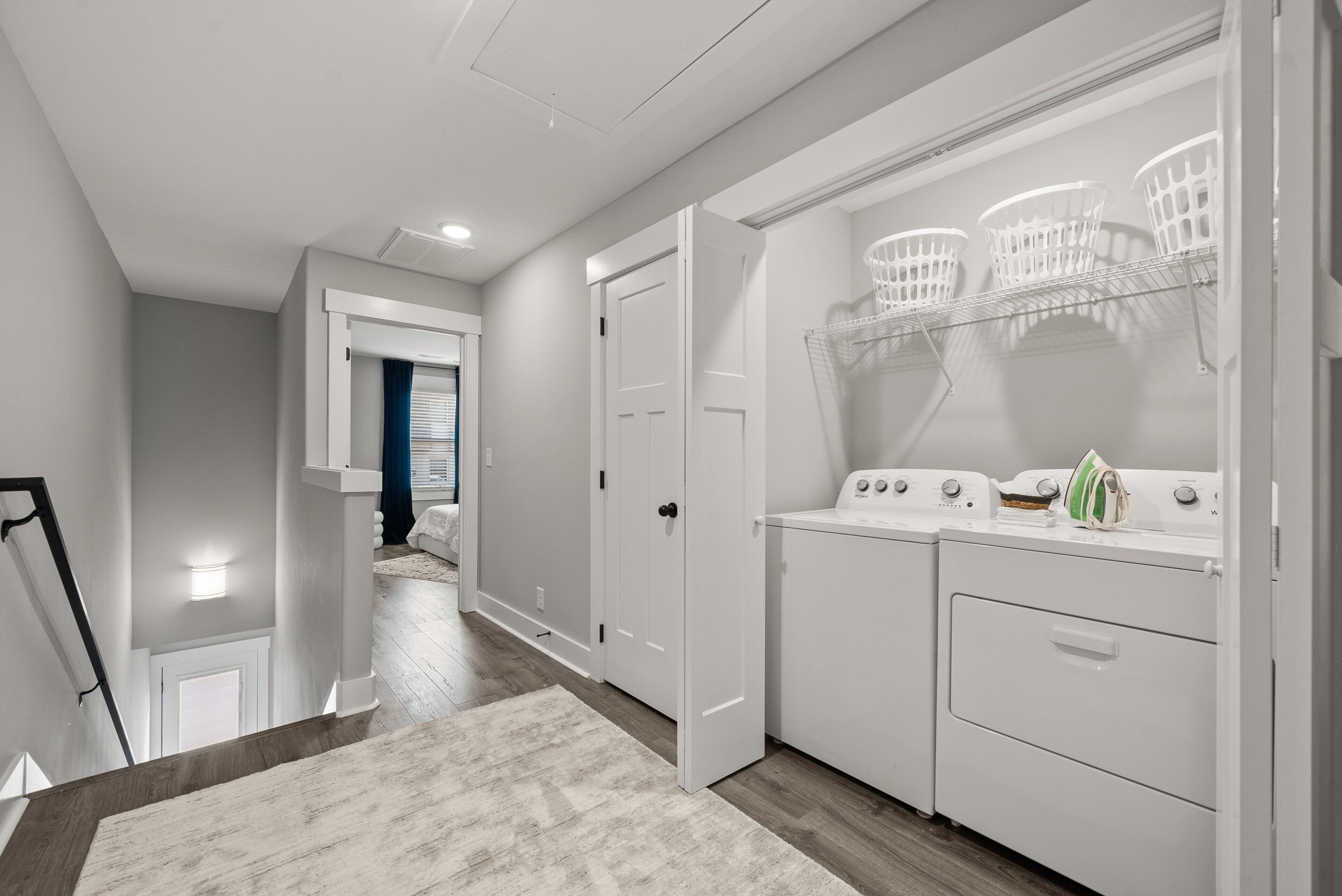 A laundry area with a washing machine, dryer, and three white baskets on a shelf.