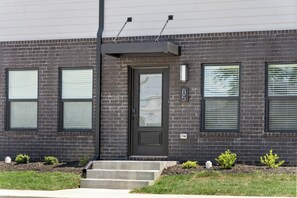 A modern two-story building with a dark brick facade, a front door with a glass panel, and three windows with blinds. - River's Edge (111 Hickory Grove BLVD) (Clarksville)