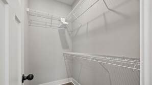 A corner of a room with a white door, a wooden floor, and a white wire shelf unit against the wall. - River's Edge (111 Hickory Grove BLVD) (Clarksville)