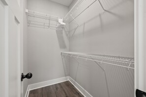A corner of a room with a white door, a wooden floor, and a white wire shelf unit against the wall. - River's Edge (111 Hickory Grove BLVD) (Clarksville)