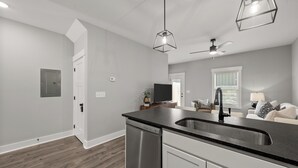 A modern kitchen with a stainless steel dishwasher, a black countertop, and a built-in sink. - River's Edge (111 Hickory Grove BLVD) (Clarksville)