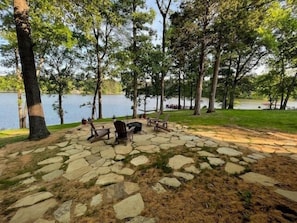 A lakeside park with stone pathways, wooden chairs, and a fire pit. - Cottage on Cypress Bay near Paris Landing State Park (Buchanan)