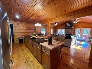A spacious kitchen with wooden cabinets, a central island, and pendant lighting. - Cottage on Cypress Bay near Paris Landing State Park (Buchanan)