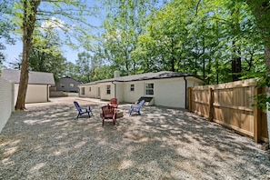 Un jardin avec une terrasse en gravier, deux chaises Adirondack rouges et une clôture en bois.