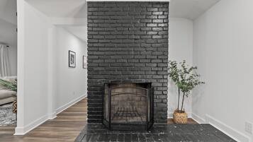 Un intérieur moderne avec une cheminée en briques noires, des murs blancs et un plancher en bois.