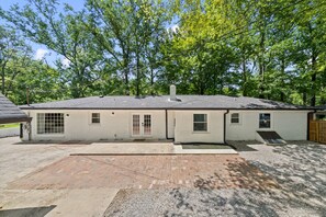 A single-story house with a brick patio, a small attached garage, and a covered porch area.