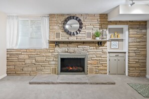 A stone fireplace with a fire, a decorative mirror, and a shelf with small items.