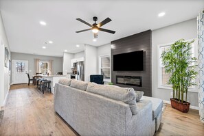Un salon moderne comprenant un canapé, un téléviseur à écran plat, un ventilateur de plafond et un coin repas.