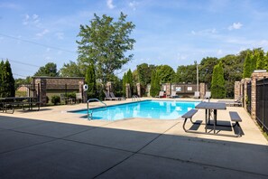 A swimming pool with a picnic table and lounge chairs.