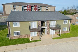 Un immeuble d’appartements à deux étages, doté d’un toit plat, de nombreux balcons et de fondations en briques.