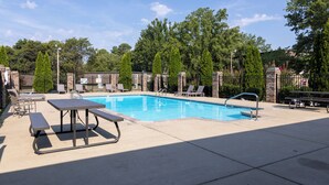 A swimming pool with lounge chairs and a picnic table.