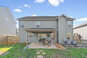 A two-story house with a covered patio area, a fenced yard, and a visible air conditioning unit. - Month-to-Month Rental (Corporate Stays) (Clarksville)