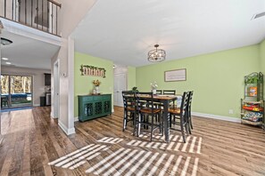 Un coin repas avec une table et des chaises en bois, un buffet vert et un lustre.