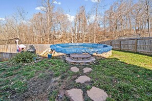 A backyard with a covered swimming pool, a wooden fence, and a stone staircase leading to a raised platform. - Month-to-Month Rental (Corporate Stays) (Clarksville)