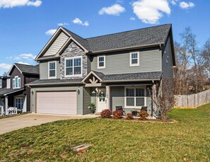 A two-story house with a garage, a stone accent wall, and a well-maintained lawn. - Month-to-Month Rental (Corporate Stays) (Clarksville)