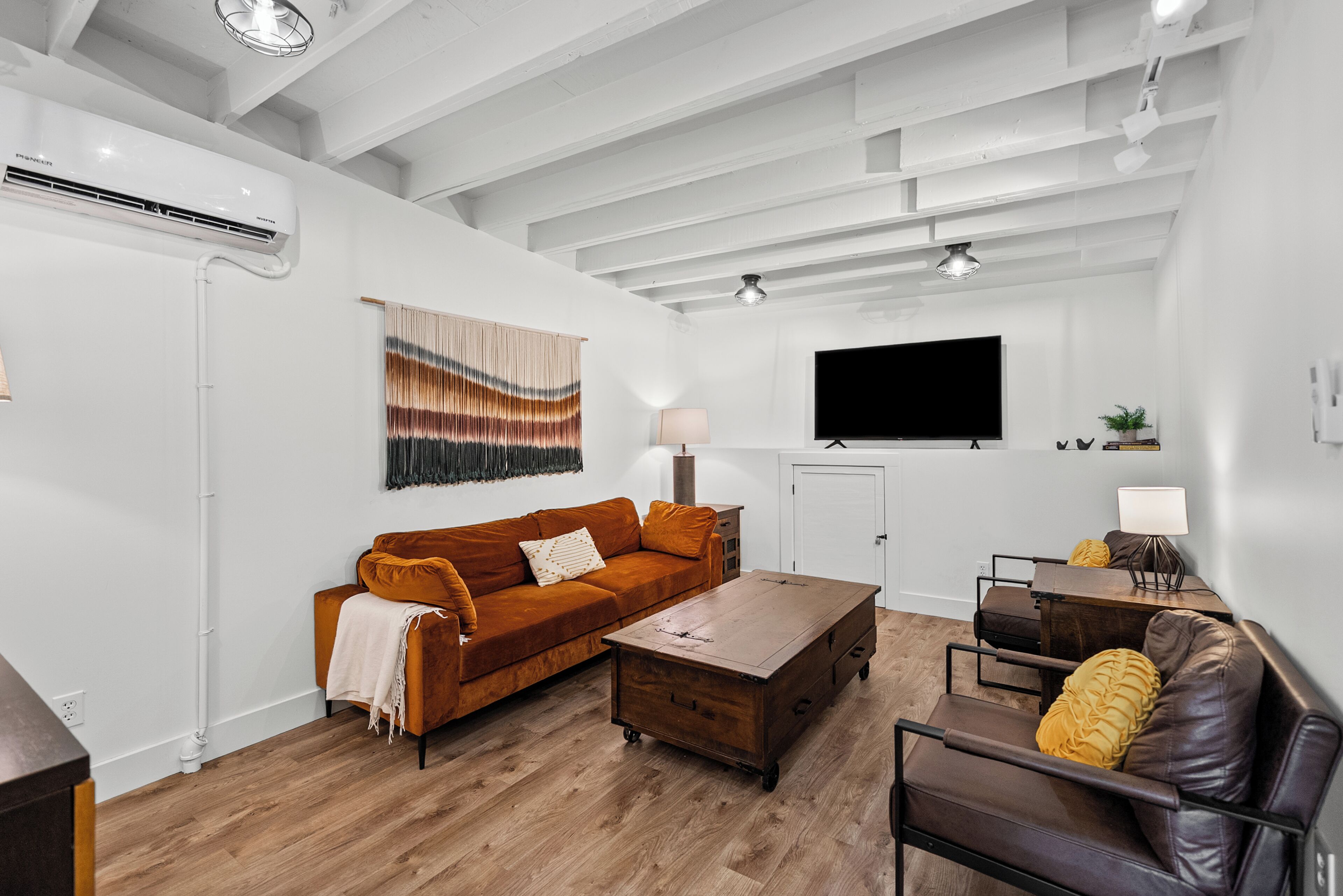 A modern living room with a sofa, coffee table, and a TV mounted on the wall.