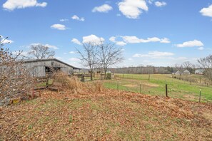 A rural landscape with a barn, open fields, and a clear sky.