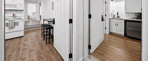Une cuisine moderne avec des meubles blancs, un lave-vaisselle en acier inoxydable et un plancher en bois.