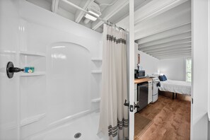 Une chambre avec une douche, un lit, un bureau avec un ordinateur et une fenêtre.