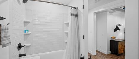 Un baño moderno con bañera, ducha y paredes cubiertas de azulejos blancos.
