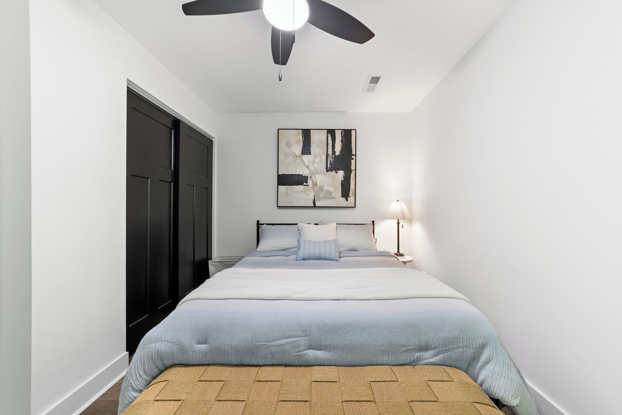 Un dormitorio con cama, ventilador de techo, lámpara de pared y puerta.