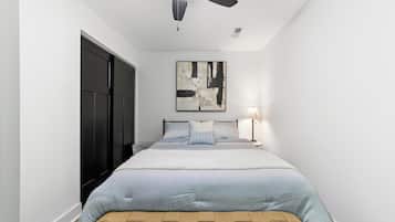 Un dormitorio con cama, ventilador de techo, lámpara de pared y puerta.
