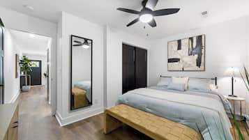 A modern bedroom with a bed, bedside table, lamp, and a ceiling fan.