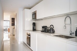 Una cucina moderna con mobili bianchi, elettrodomestici in acciaio inossidabile e forno a microonde integrato.