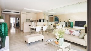 A modern living space with a dining area, kitchen, and a sofa with a vase of flowers. - Upstays Croisette 75m² 2Br with terasse (Cannes)