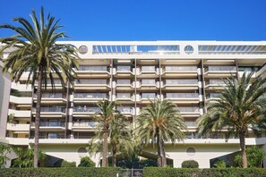 Ein mehrstöckiges Hotel mit Balkonen, Palmen und blauem Himmel.