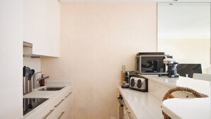 A compact kitchen with a built-in stove, a coffee maker, and a toaster. - Upstays Croisette 75m² 2Br with terasse (Cannes)