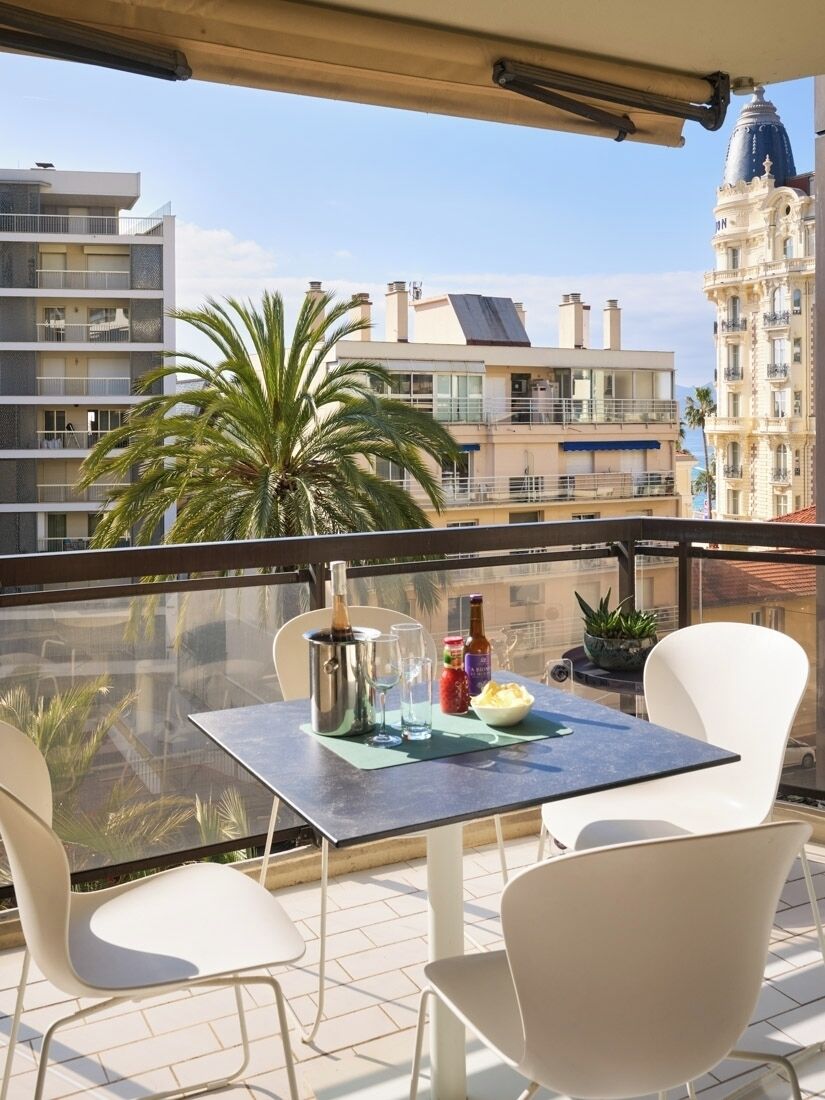 Ein Balkon mit Tisch für zwei Personen, einer Champagnerflasche und einer Schüssel mit Snacks.