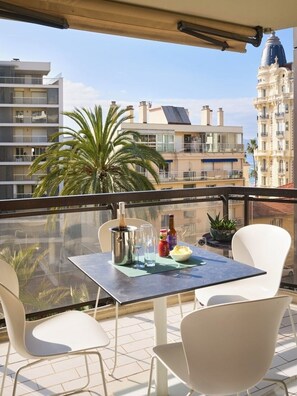 Ein Balkon mit Tisch für zwei Personen, einer Champagnerflasche und einer Schüssel mit Snacks.