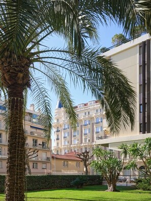 Ein Gebäude mit moderner Fassade, umgeben von gepflegter Bepflanzung und Palmen.