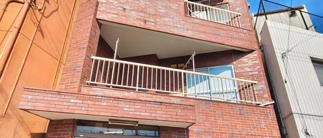 A multi-story building with a brick facade, a ground-level entrance, and a visible air conditioning unit outside.