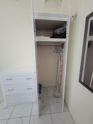 Een witte kast met een onderkast, een kledingroede en een klein ladeblok.