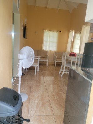 A room with a tiled floor, white furniture, a white fan, and a black refrigerator. - ​Country Green — A Peaceful Saint Lucian Countryside Getaway (Castries)