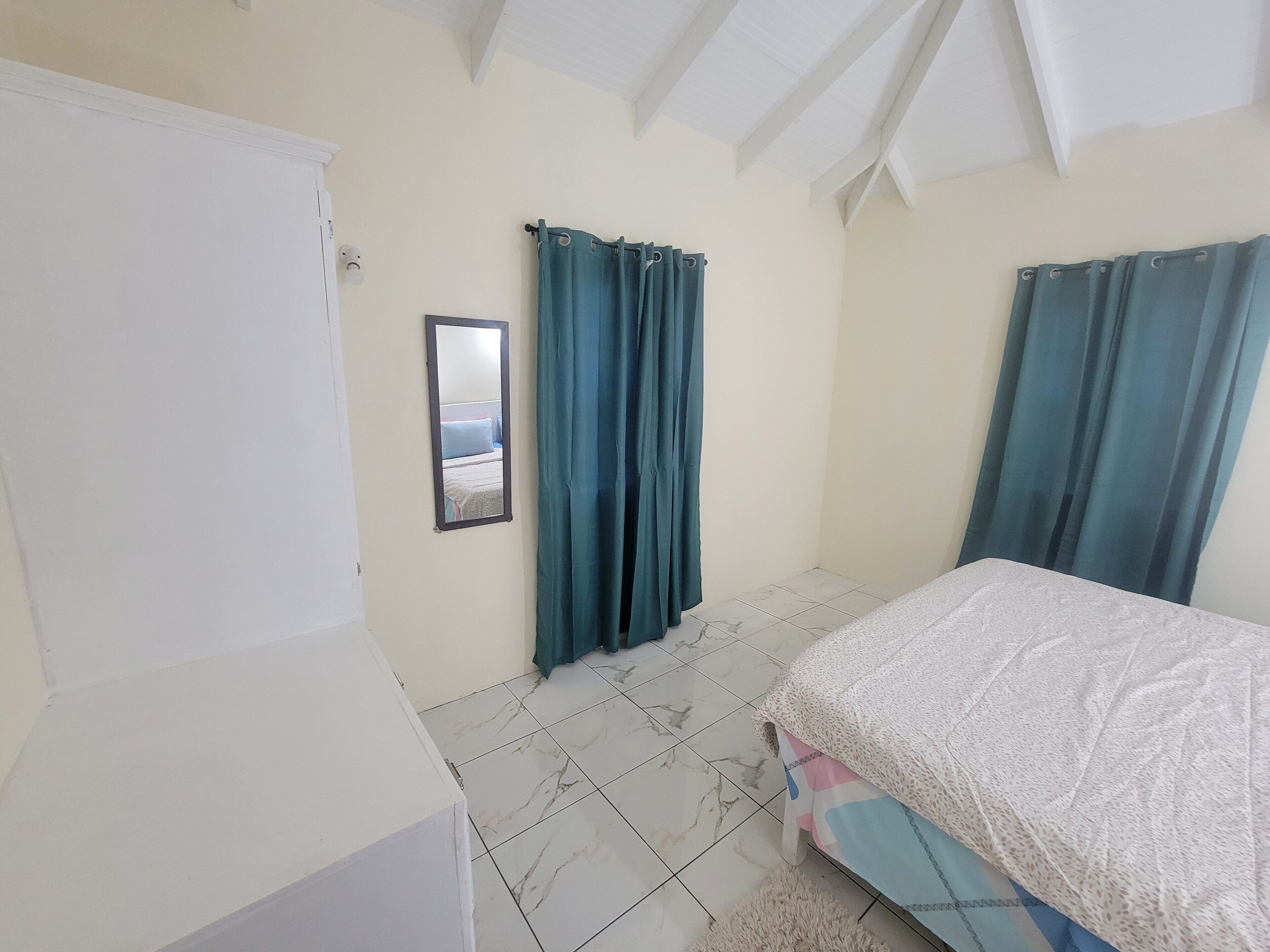 Un dormitorio con cama, armario, espejo y cortinas.