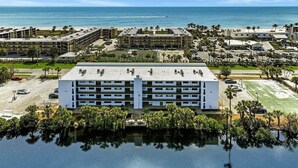 Un hotel a più piani con un cortile interno, un parcheggio e vista sull'oceano.