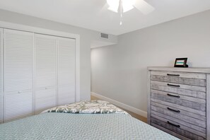 A bedroom with a bed, a dresser, and a closet.
