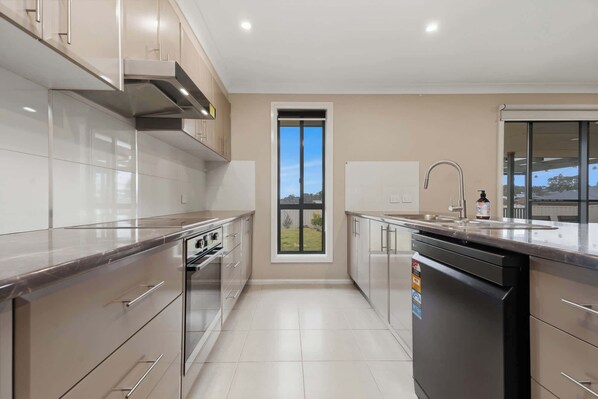 A modern kitchen with stainless steel appliances, a dishwasher, and a window providing a view of the outdoors.
