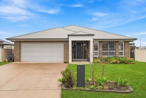 A residential house with a garage, a front door, and a well-maintained lawn. - Robinson Retreat - Sleeps 8, Pet Friendly (Orange)