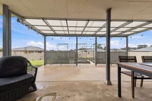 A covered patio area with a concrete floor, a dining table, and a sofa. - Robinson Retreat - Sleeps 8, Pet Friendly (Orange)