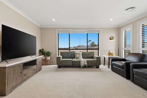 A living room with a flat-screen TV, a sofa, a coffee table, and a window with blinds. - Robinson Retreat - Sleeps 8, Pet Friendly (Orange)
