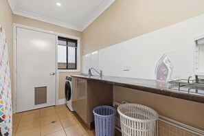 A compact kitchen with a washing machine, a sink, and a window. - Robinson Retreat - Sleeps 8, Pet Friendly (Orange)