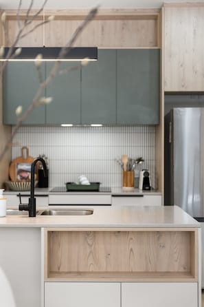 A modern kitchen with a stainless steel refrigerator, a built-in oven, and a wooden countertop.