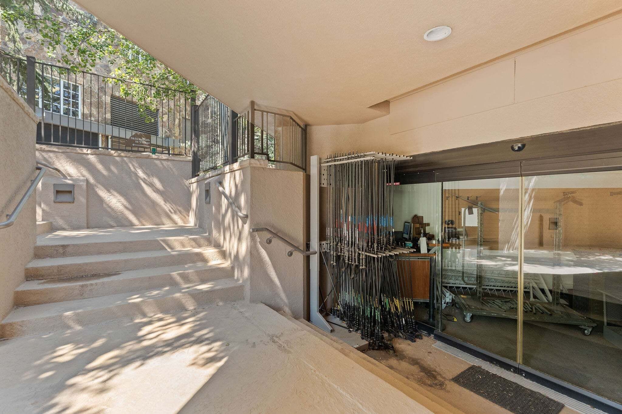 A staircase leading to a building entrance with a metal railing and a glass door.