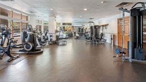 Ett rymligt gym med konditionsmaskiner, fria vikter och en vägg full av speglar.