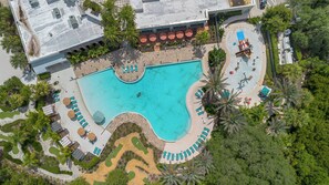 An aerial view of a resort with a large central pool, sun loungers, and palm trees. - 4BR Family Townhome, pool, resort & Splash (Davenport)