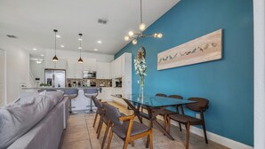 Una cocina moderna con armarios blancos, un refrigerador de acero inoxidable y un microondas empotrado.